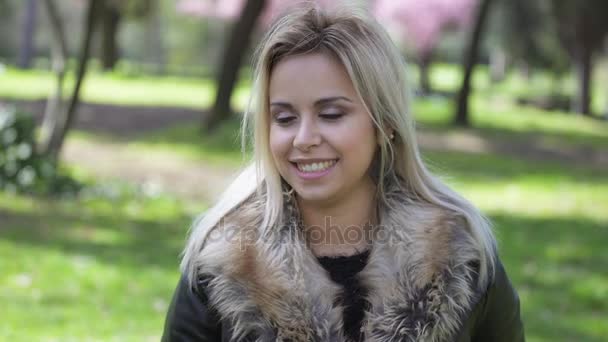 Classy blonde woman at the park smiles at the camera — Stock Video