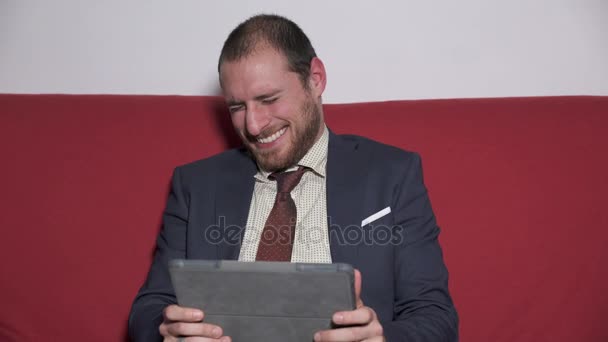 Affärsman läser något roligt på tabletten och börjar skratta — Stockvideo