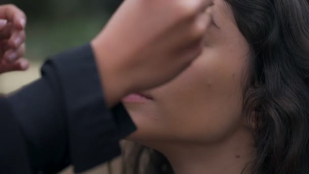 Appliquer le maquillage avec un pinceau sur le visage de la jeune femme, fermer — Video