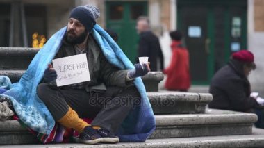 evsiz basamaklarında oturan bir adam tarafından sadaka alır