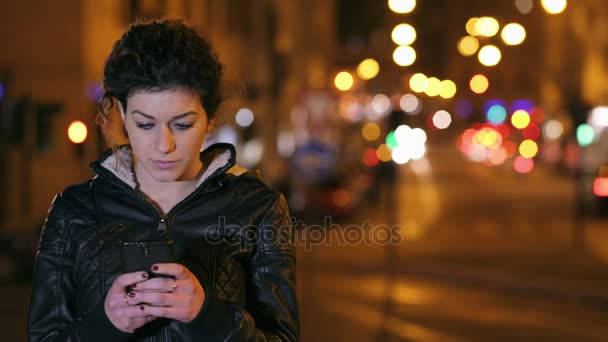Solitario pensativo mujer escribiendo en smartphone ciudad por la noche — Vídeos de Stock