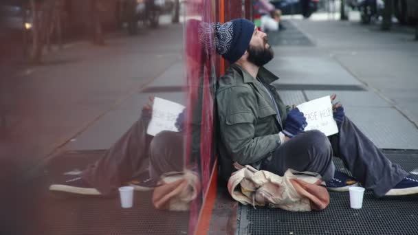 Gelangweilte traurige Obdachlose, die auf der Straße sitzen und auf Wohltätigkeit warten — Stockvideo