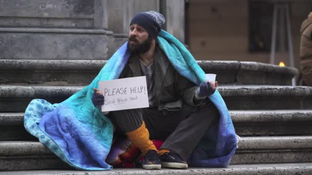 Einsame Obdachlose, die auf den Stufen sitzen und jemanden bitten, ihm Münzen zu geben — Stockvideo