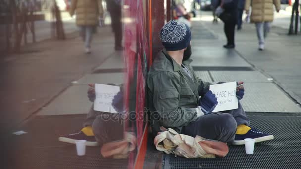 Одинокие бездомные читают книгу, сидя на улице — стоковое видео