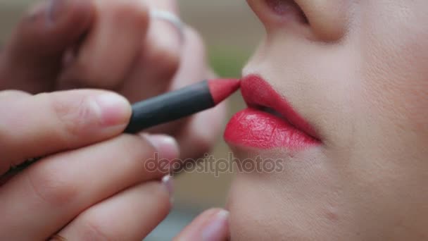 Рука художника макіяжу наносить червоний олівець на рот жінки — стокове відео