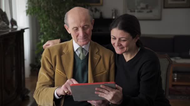 Portrait de famille : vieux père souriant et sa fille regardant des photos sur tablette — Video