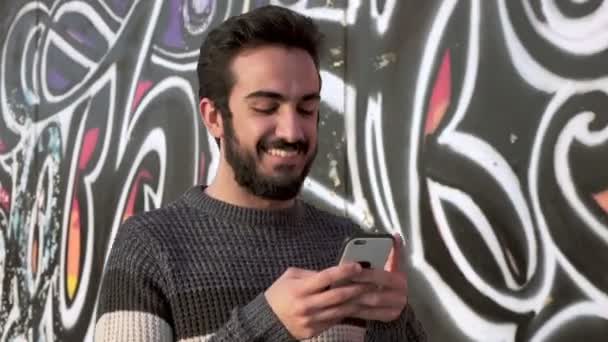 Sonriente joven latino caminando en la calle charlando — Vídeos de Stock