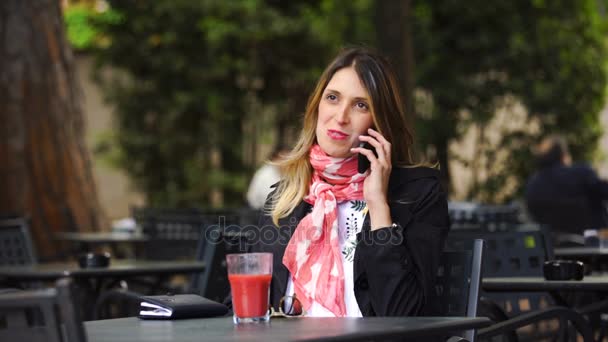 Mulher muito sorridente falando em um smartphone e bebendo no café ao ar livre — Vídeo de Stock