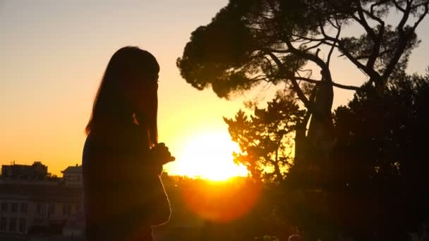 De magie van de zonsondergang over de stad: eenzame vrouw overweegt de ondergaande zon — Stockvideo