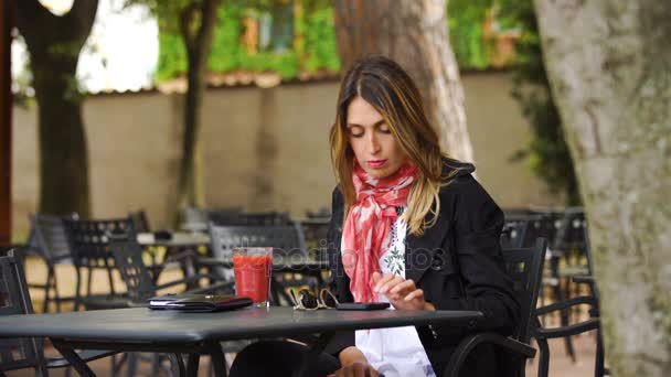 Улыбающаяся милая блондинка проверяет и печатает на своем смартфоне в баре — стоковое видео