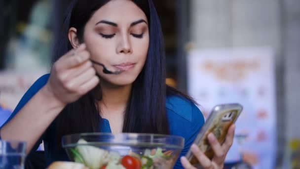 レストランと答え、携帯電話でのアジア女性を食べるサラダ — ストック動画