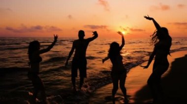 Siluet, dört arkadaş dans üzerinde Ocean Beach, Sunset