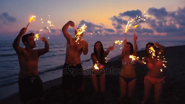 Porträt von Freunden mit Wunderkerzen feiern, lachen und tanzen am Strand — Stockvideo