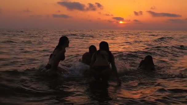 Grupo de jóvenes bañándose y bromeando en la fiesta de playa al atardecer . — Vídeos de Stock