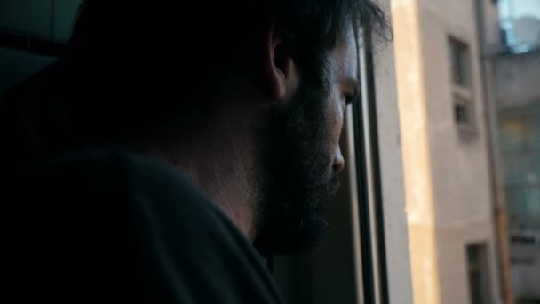 Λυπημένος άνθρωπος στο παράθυρο σκέπτεται την πόλη — Αρχείο Βίντεο