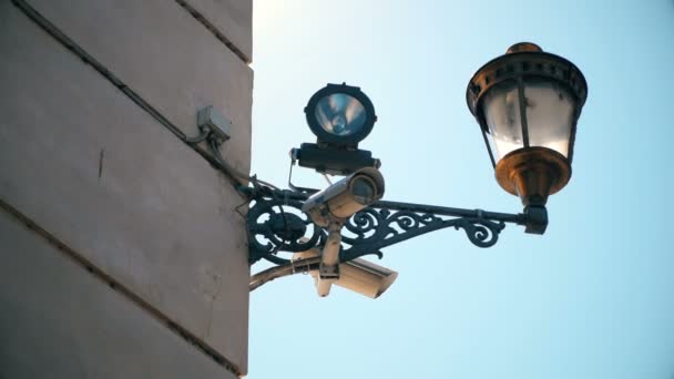 La cámara de video de vigilancia en la pared del edificio controla la ciudad — Vídeos de Stock