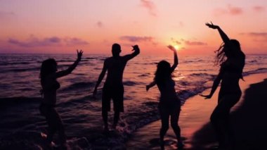 Siluet, dört arkadaş dans üzerinde Ocean Beach, Sunset