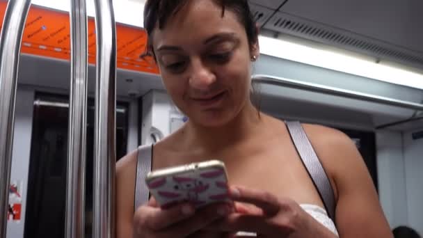 Lächelnde Frau tippt während U-Bahn-Fahrt auf Smartphone — Stockvideo