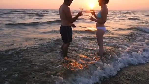 Летняя любовь: молодая пара тостится на закате моря — стоковое видео