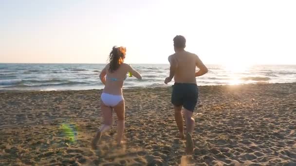 De vreugde en de zorgvuldigheid van de zomer: een jong koppel op het strand loopt naar de zee — Stockvideo