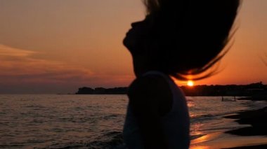 Saçlarını günbatımında sallayarak kafasını yetiştirme kadın siluet