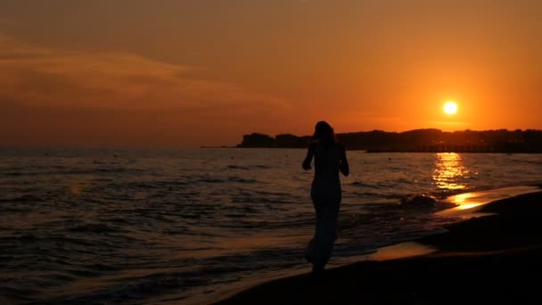 Siluett av kvinna kör vid solnedgången på stranden — Stockvideo