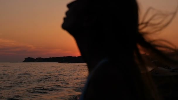 Donna silhouette tira la testa muovendo i capelli al tramonto sulla spiaggia — Video Stock