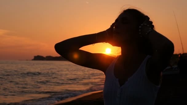 Silueta ženy, uvolněné ruce vlasy rukama při západu slunce na pláži — Stock video