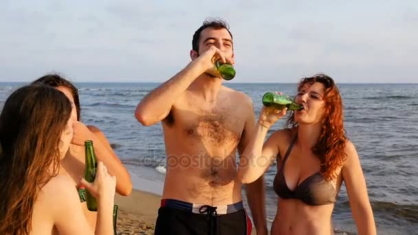 Радость лета: смеющиеся друзья пьют пиво на пляже — стоковое видео