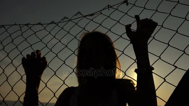 Silhouette of desperate woman imprisoned behind a net — Stock Video