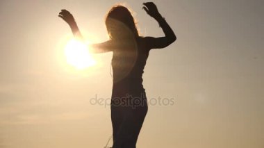 Gün batımında sahilde dans duygusal ve güzel kadının siluet