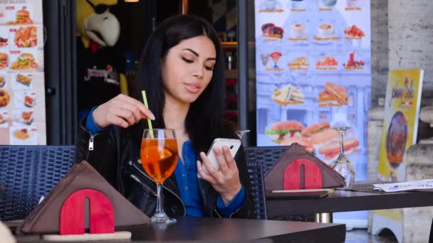 Lachende en schattig Aziatische vrouw met behulp van smartphone e mengen haar drankje-buiten — Stockvideo