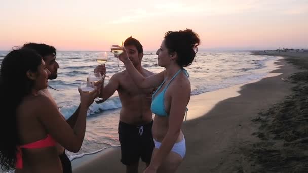Sommersonnenuntergang: Vier glückliche Freunde am Strand stoßen gemeinsam an und trinken