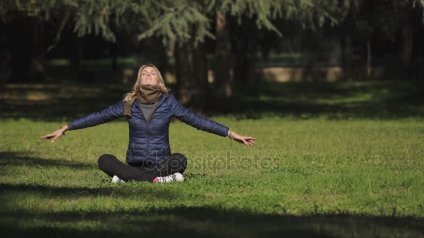 Portrait de femme blonde saine assise dans le parc faisant du yoga — Video