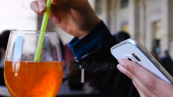Закрыть на женской руке СМС на смартфоне и смешать коктейль - открытый — стоковое видео