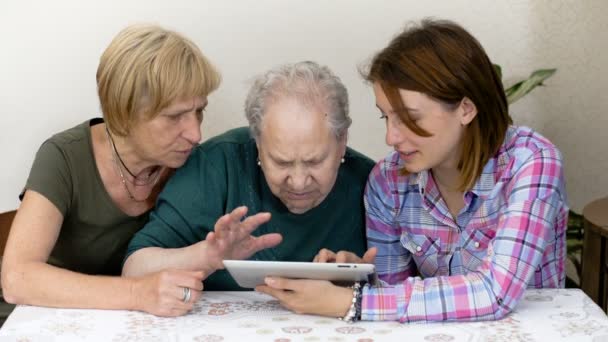 Neta e filha ajudando a avó a usar o tablet digital — Vídeo de Stock