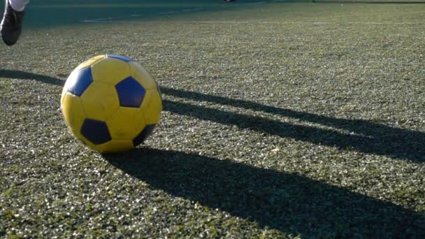 Joven chico pies pateando pelota de fútbol durante un partido — Vídeos de Stock