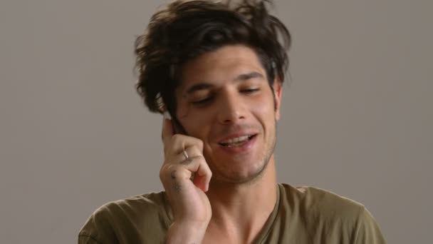 Милый и улыбающийся молодой человек разговаривает по телефону, крупным планом — стоковое видео