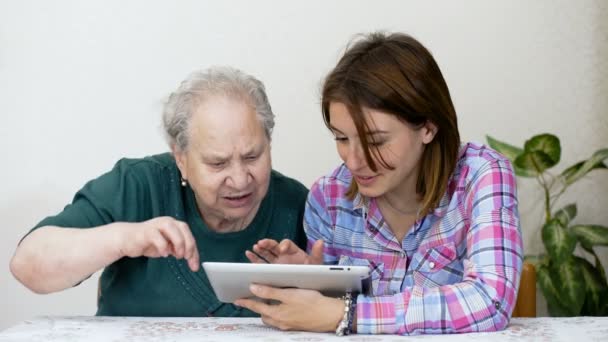 Jonge grandaughter lesgeven aan haar grootmoeder aan de tablet gebruiken — Stockvideo