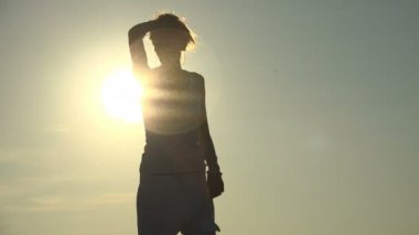 Yaz özgürlük: güzel bir kadın silueti günbatımında dans