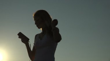 Kadın arkadan aydınlatmalı smartphone ve dans müzik dinle