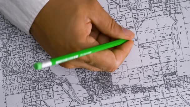 Χέρι σηματοδοτεί ένα site με ένα μολύβι στο χάρτη — Αρχείο Βίντεο