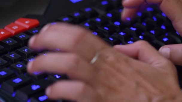 Woman's hands typing Blue illuminated keyboard — Stock Video