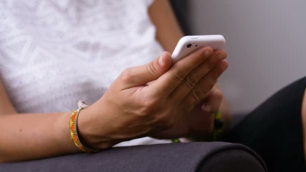 Frau sitzt auf Stuhl und schreibt SMS auf ihrem Smartphone — Stockvideo