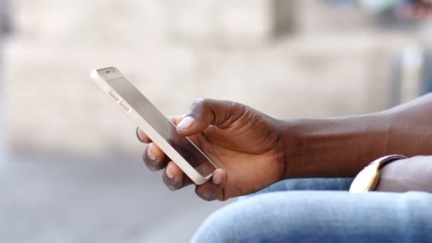 Рука чернокожего человека, сидящего на смартфоне — стоковое видео