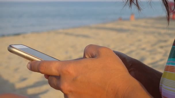 Νεαρή Γυναίκα Πληκτρολόγηση Smartphone Στην Παραλία — Αρχείο Βίντεο