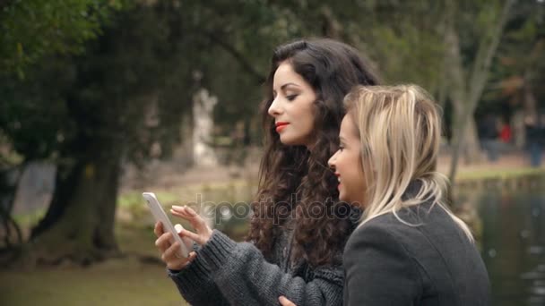 Dos Novias Divierten Parque Viendo Fotos Teléfono Inteligente — Vídeo de stock