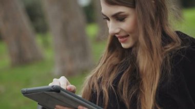 genç kadın parkta tablet kaydırma güzel