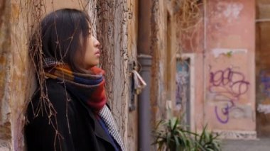 Bir duvara yaslanmış depresif ve üzgün Çinli kadın tek başına,
