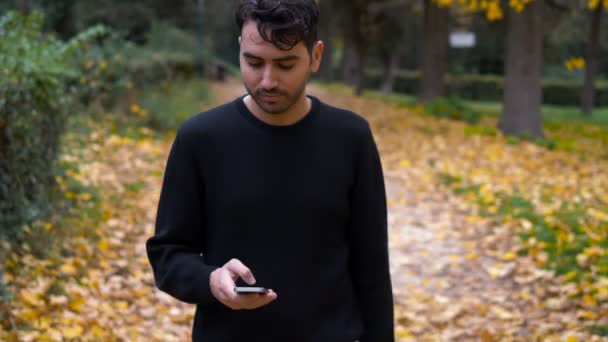 Giovane Uomo Che Sveglia Nel Parco Digitando Sul Suo Smartphone — Video Stock